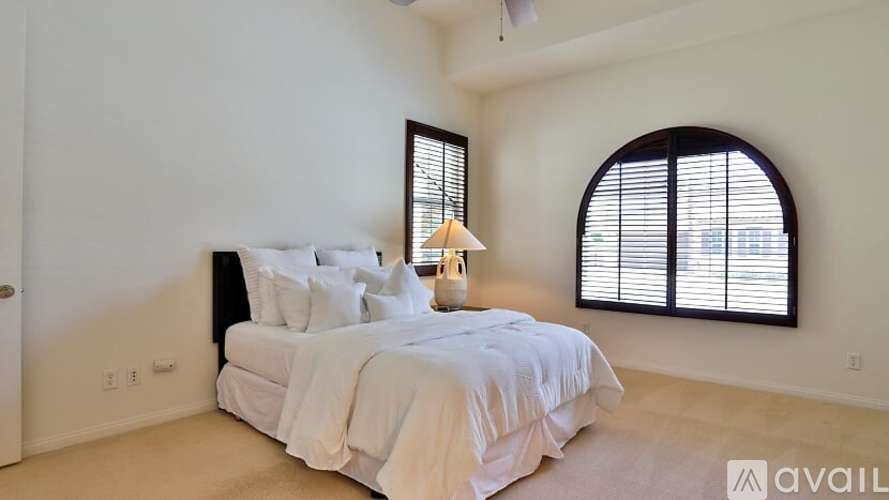A bedroom with a large bed and a window with blinds.