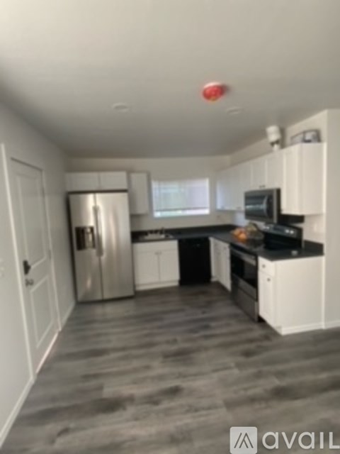A kitchen with white cabinets and a stainless steel refrigerator.