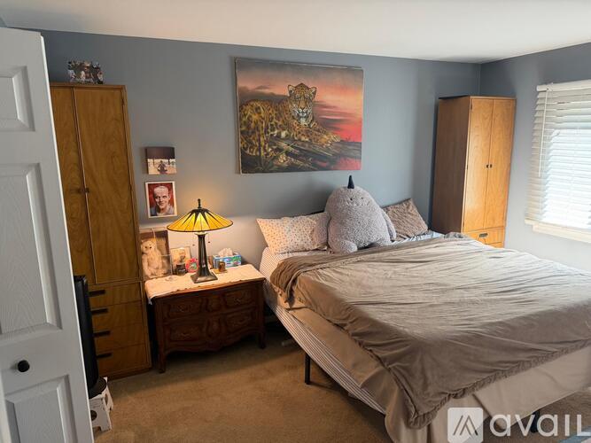 A bedroom with a bed, nightstand, and a painting on the wall.