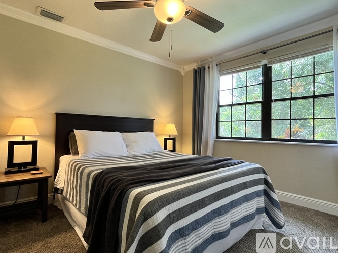 A bedroom with a bed, two lamps, and a ceiling fan.