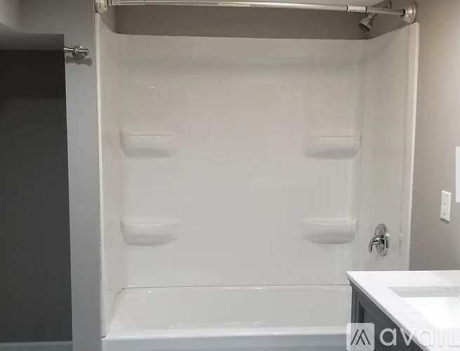 A white bathtub is in a bathroom with a white sink.