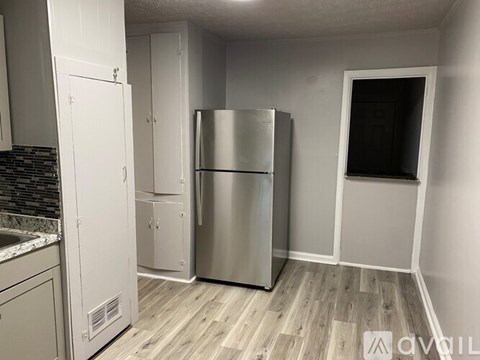 A kitchen with a stainless steel refrigerator and white cabinets.