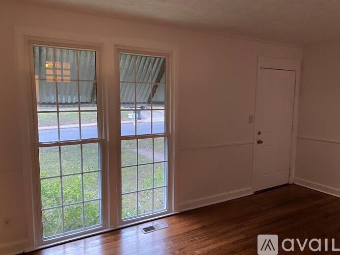A room with a white door and two windows with a view of the street.