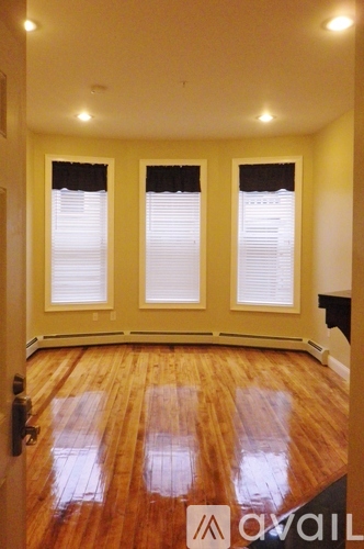 A room with wooden floors and three windows.