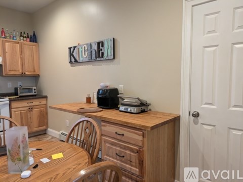 A kitchen with a wooden table and chairs, a microwave, a toaster, and a coffee maker.
