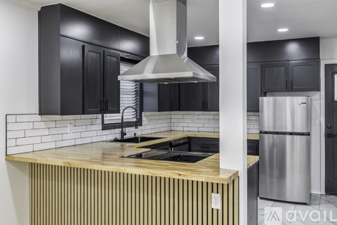 A modern kitchen with black cabinets and a wooden island.