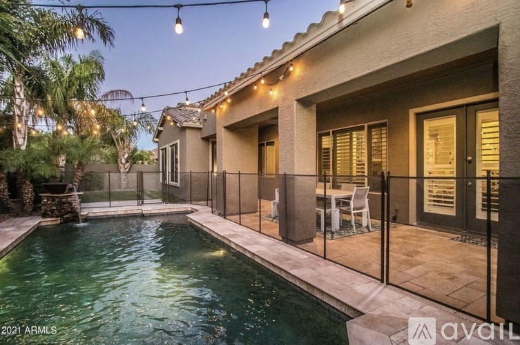 A pool in a backyard with lights strung above it.
