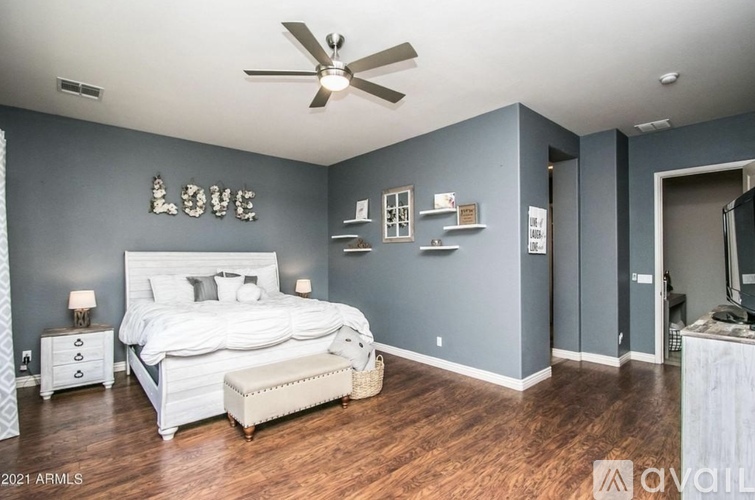 A bedroom with a large bed and a ceiling fan.
