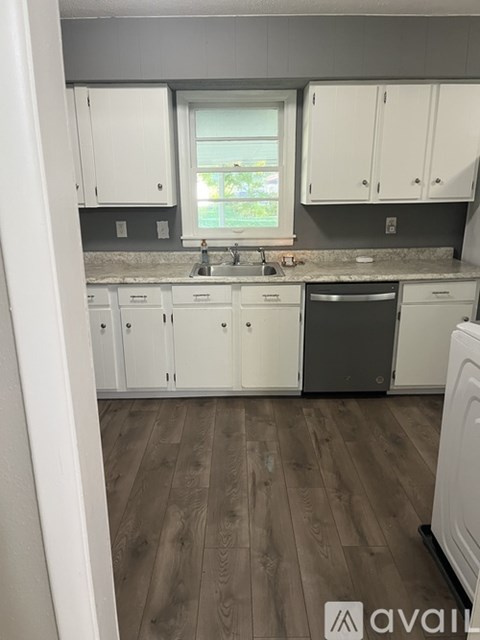 A kitchen with white cabinets and a wooden floor.