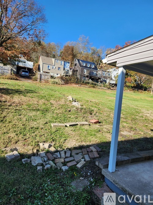 A grassy area with a stone wall and a house in the background.