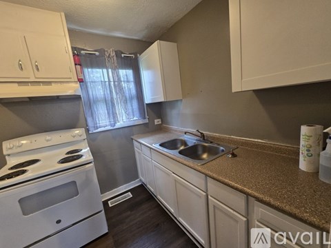 A kitchen with white cabinets and a white stove top oven.