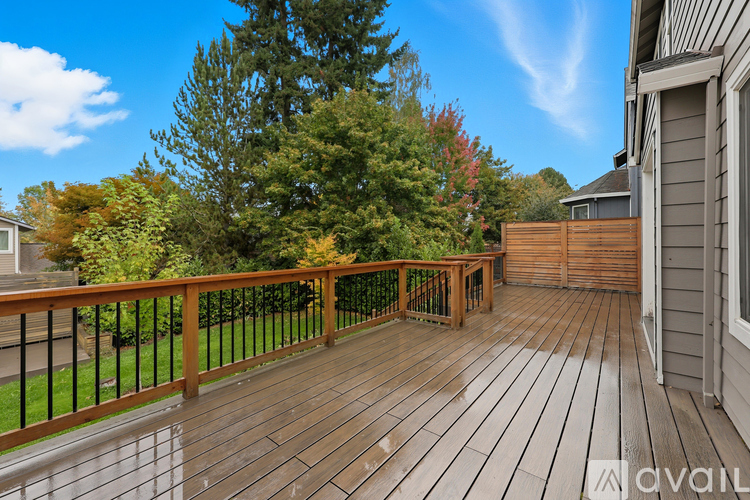 A wooden deck with a railing and a bench is surrounded by trees.