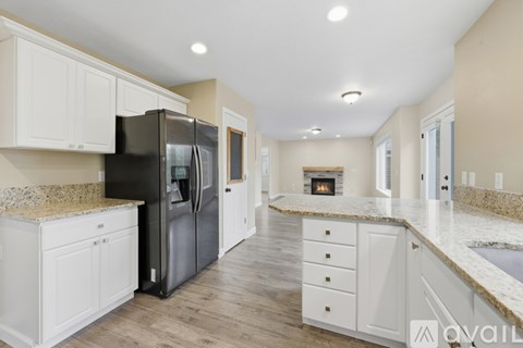 A kitchen with a black refrigerator and white cabinets.