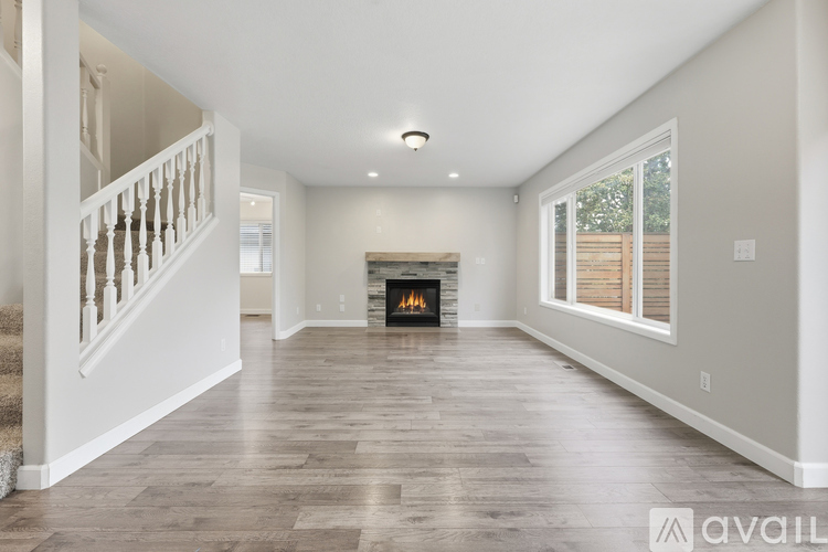 A spacious living room with a fireplace and a staircase on the left side.