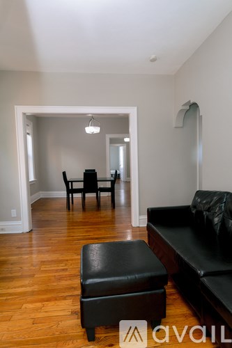 A living room with a black leather couch and ottoman.