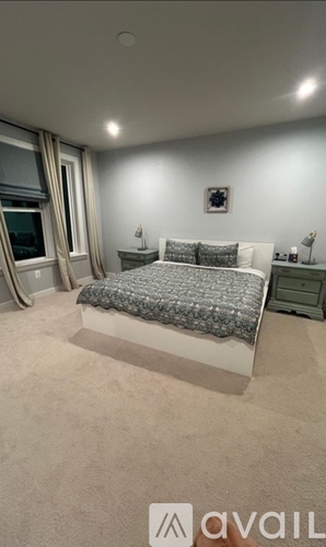 A bedroom with a bed, nightstands, and a window.