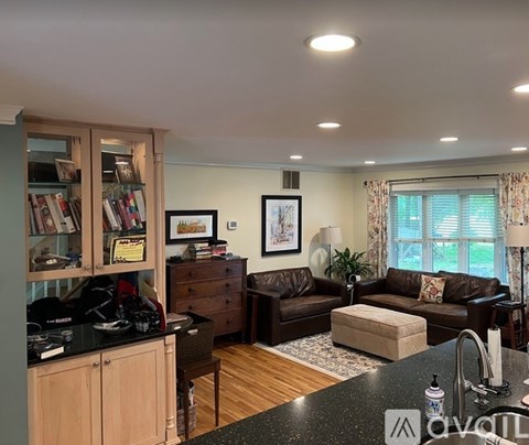 A living room with a brown leather couch and a black countertop.