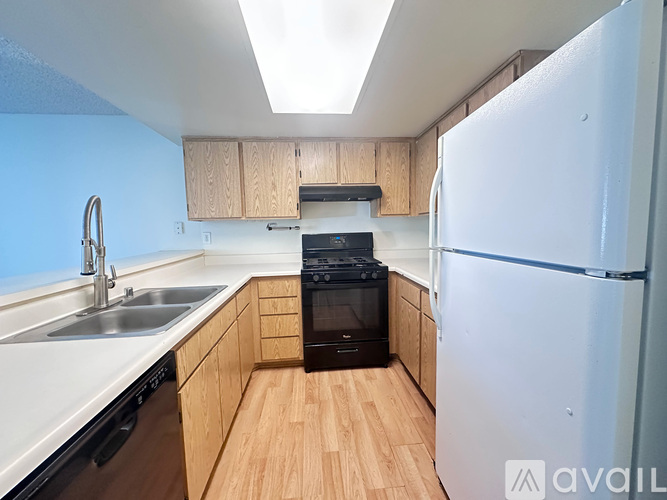 A kitchen with a white refrigerator, black oven, and wooden cabinets.