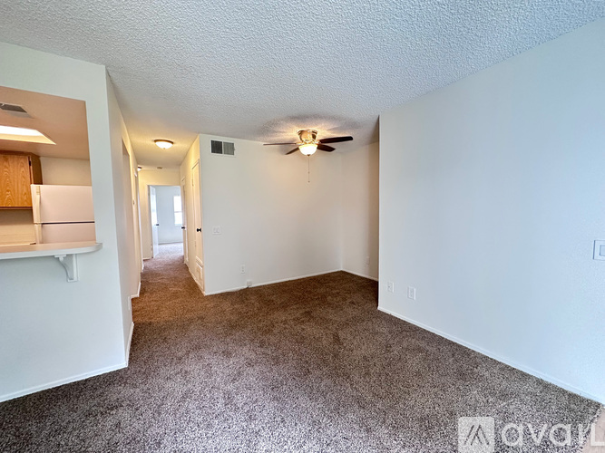 A spacious room with a ceiling fan and carpeted floor.