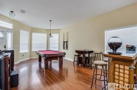A room with a pool table and a bar area.