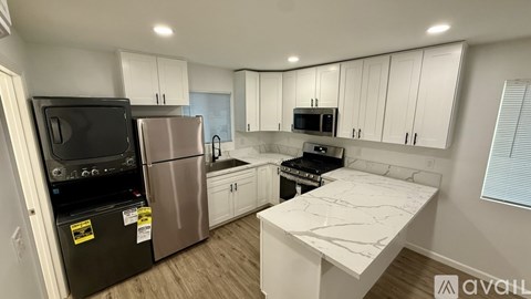 A kitchen with white cabinets and a black fridge.