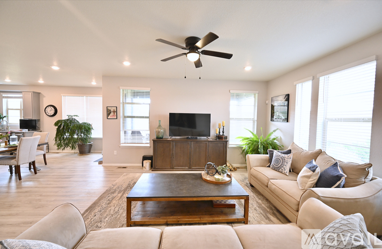 A living room with a couch, coffee table, and a ceiling fan.