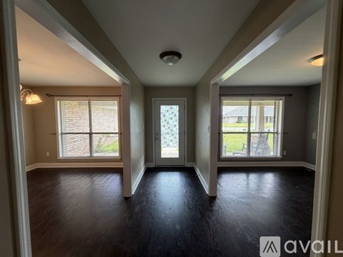 A spacious room with hardwood floors and large windows.