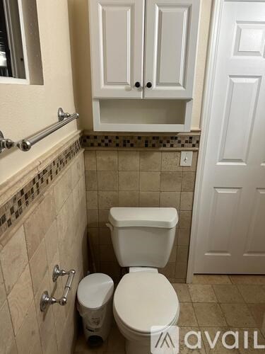 A white toilet sits in a bathroom next to a white cabinet.