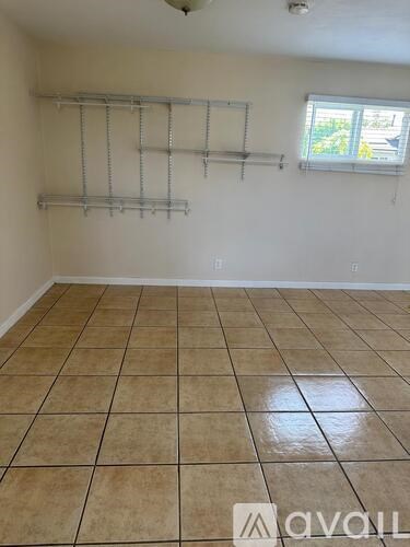 Empty room with tiled floor and shelving unit.