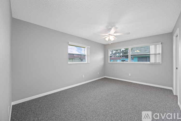 A room with a carpeted floor and a window with a view of a building outside.