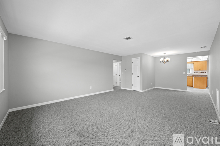 A spacious room with grey carpeting and white walls.