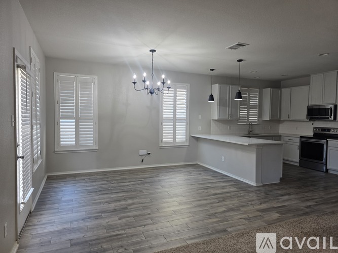 A spacious kitchen and living room with wooden floors and white shutters.