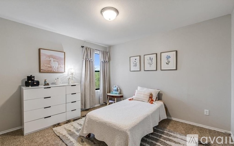 A bedroom with a white bed, dresser, and nightstand with a window and curtains.