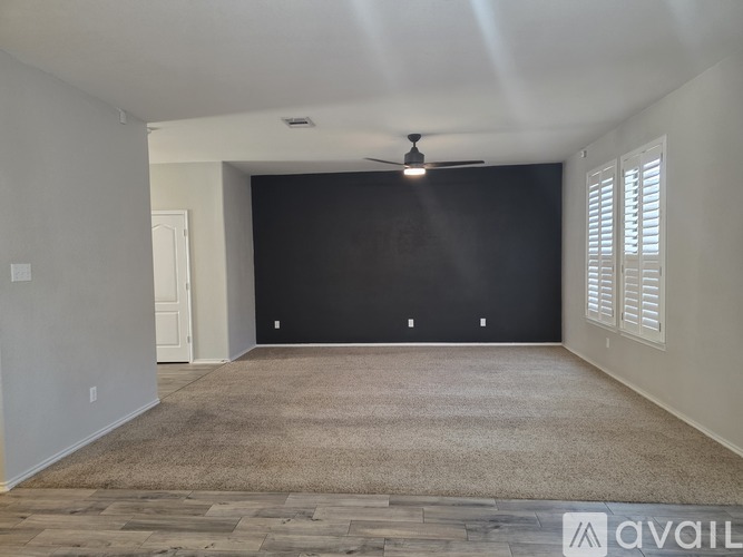 A spacious room with a ceiling fan and a carpeted floor.