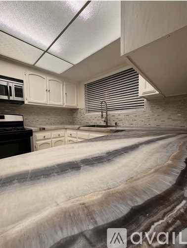 A kitchen with white cabinets and a marble countertop.