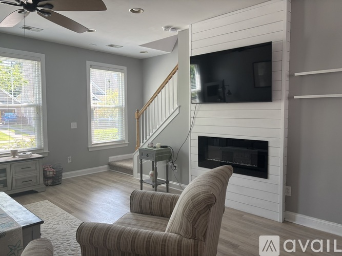 A living room with a striped chair facing a fireplace.