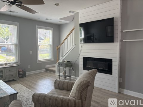 A living room with a striped chair facing a fireplace.