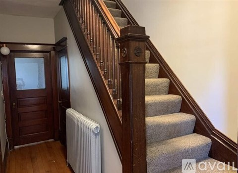 A staircase with a wooden banister and a grey carpeted runner.