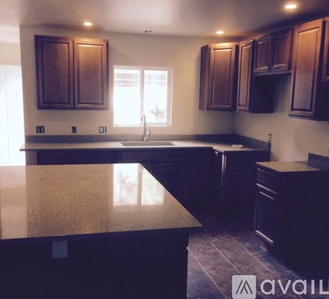 A kitchen with dark wood cabinets and a granite countertop.