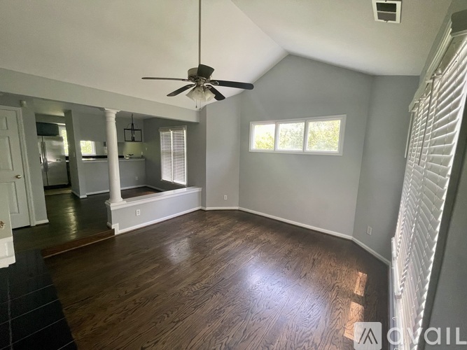 A room with a ceiling fan and hardwood floors.