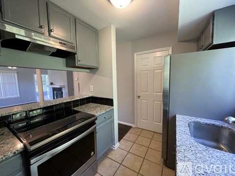A kitchen with a black stove top oven and a white door.