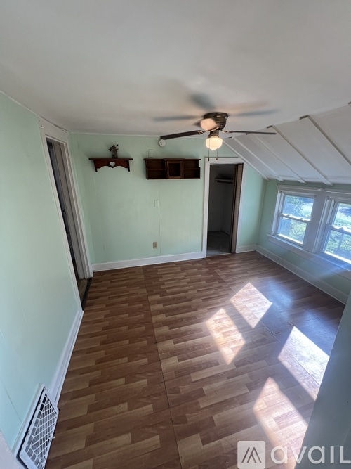 A room with a ceiling fan and wooden flooring.