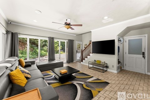 A living room with a grey couch and a black and yellow rug.