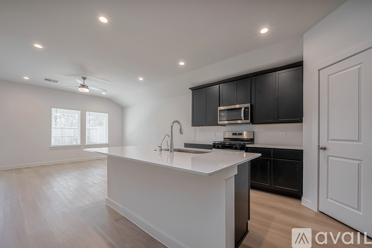A modern kitchen with black cabinets and a white island.