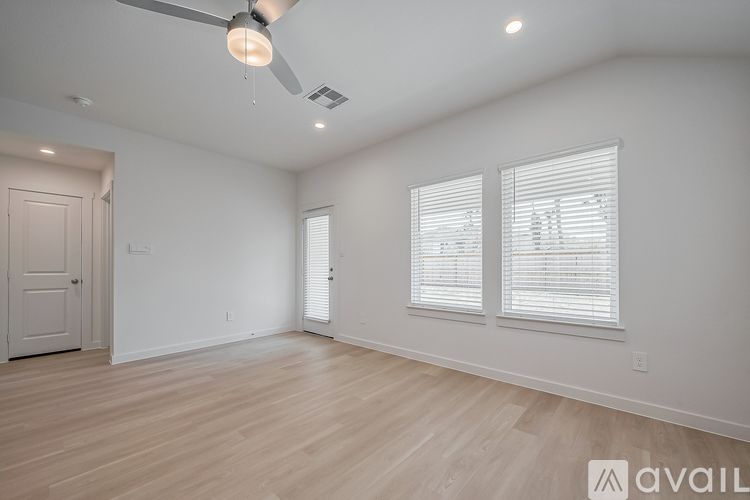 A spacious room with a ceiling fan and three windows.