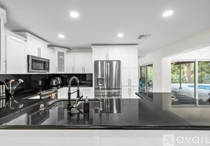 A modern kitchen with a black countertop and stainless steel appliances.