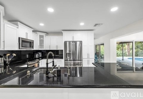 A modern kitchen with a black countertop and stainless steel appliances.