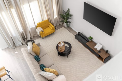 A living room with a yellow chair and a black TV.