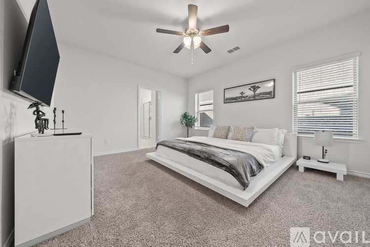 A bedroom with a large bed and a ceiling fan.