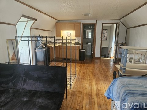 A living room with a black couch and a wooden floor.